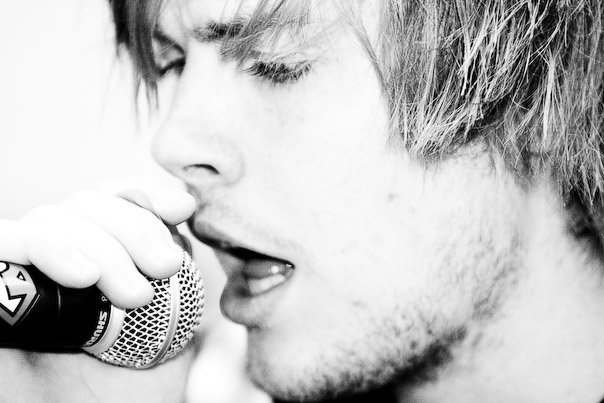 A close-up side profile of a person singing into a microphone.