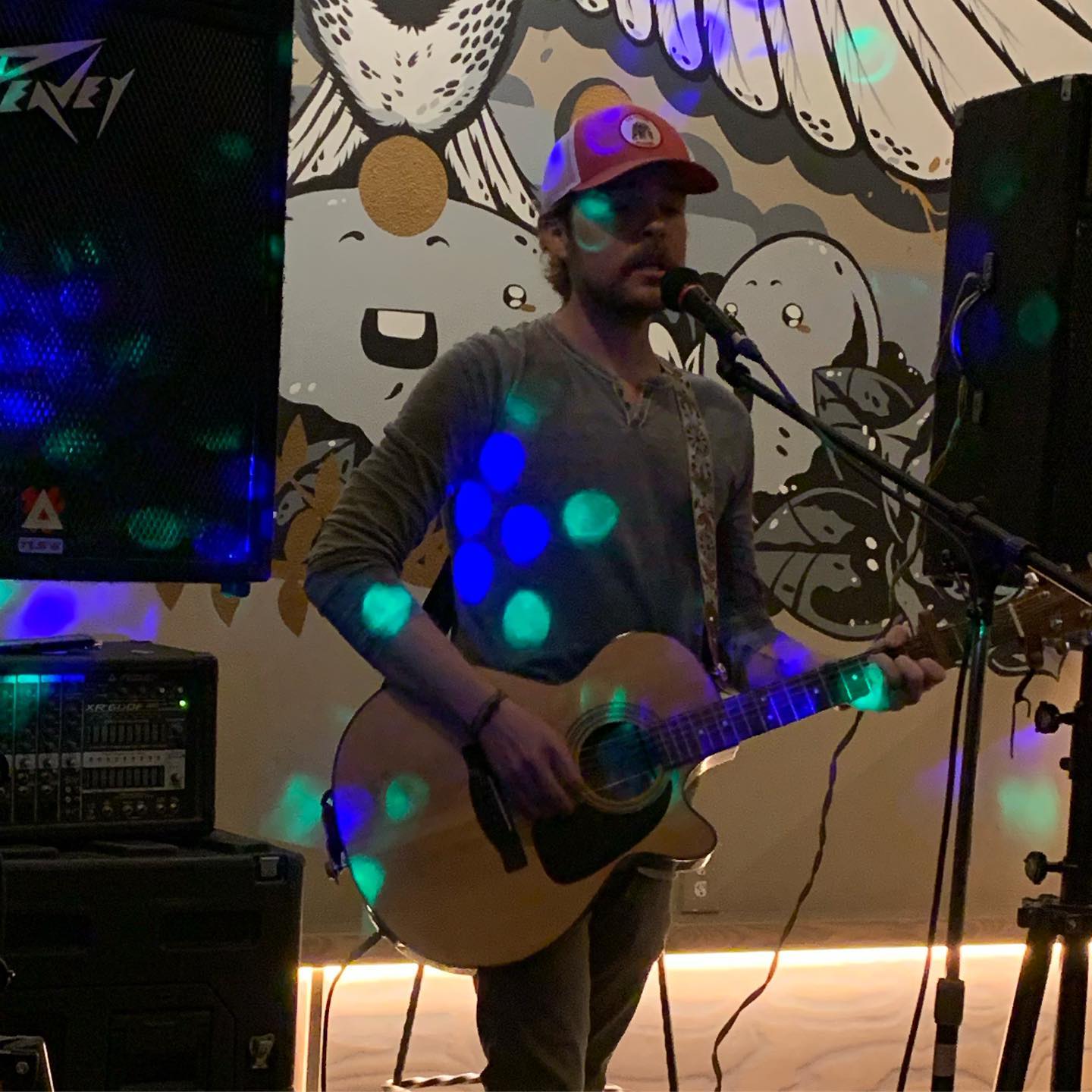 A guitarist playing an electric guitar on stage with blue lighting effects visible.