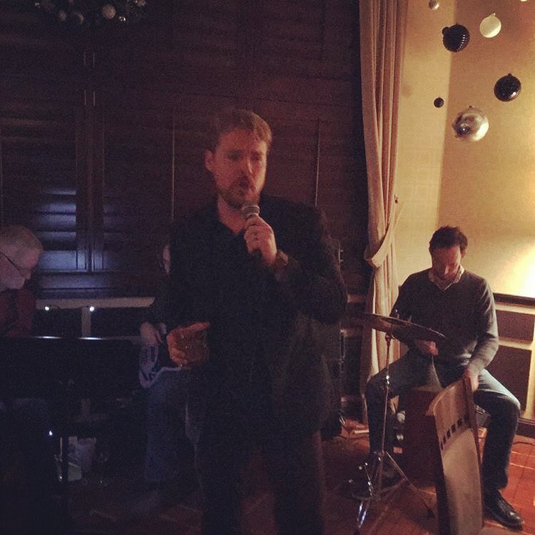 A close-up side profile of a person singing into a microphone.